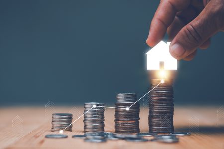 Investment for real estate concept, Businessman's hand putting house icon on top of coins stack and progressing graph, Savings money for buy house, budgeting, investment for the future.